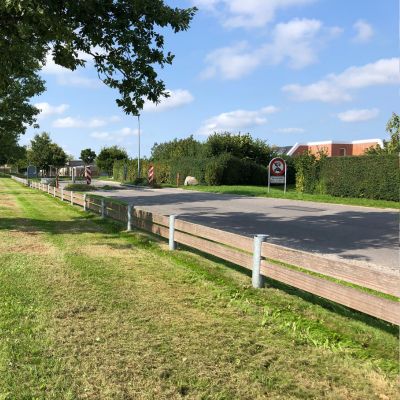 Et minimalistisk fodhegn i mørkegråt stål fra Peoples, der elegant afgrænser et fortovsområde fra en cykelsti.